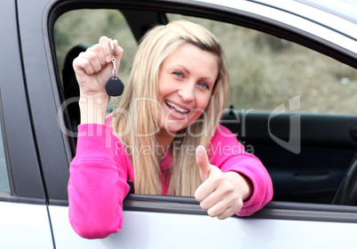 Happy female driver showing a key after bying a new car