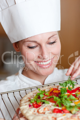 Smiling female chef preparing a pizza