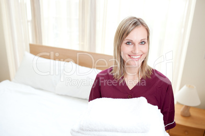 Radiant cleaning lady holding towels in a hotel room