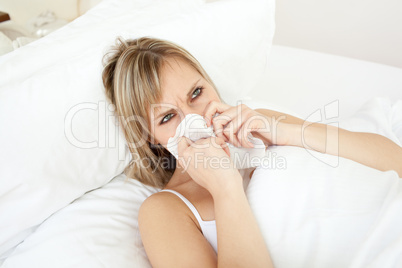 Sick young woman blowing lying on her bed