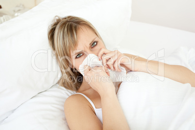 Sick blond woman blowing lying on her bed