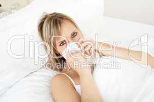 Sick blond woman blowing lying on her bed