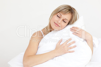 Relaxed woman hugging her cushion sitting on her bed