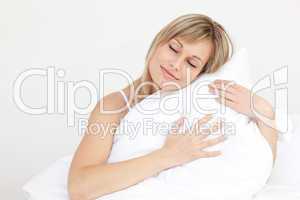 Relaxed woman hugging her cushion sitting on her bed