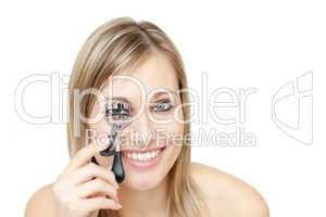 Smiling woman using an eyelash curler