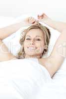 Cheerful blond woman resting lying on a bed