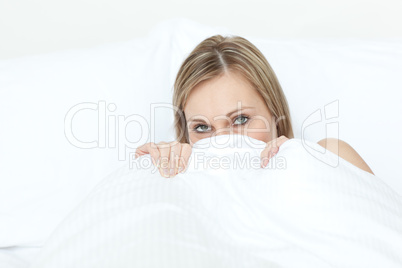 Radiant blond woman hiding in her bed