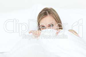 Radiant blond woman hiding in her bed
