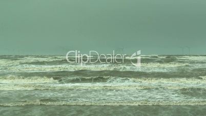 Stormy waves on the river with wind turbines in the background 6