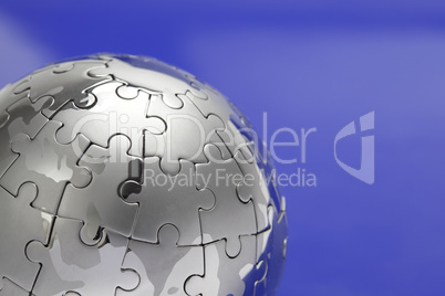 Puzzle- Globus, close- up vor blauem Hintergrund