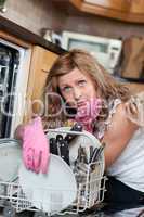 Tired blond woman filing the dishwasher