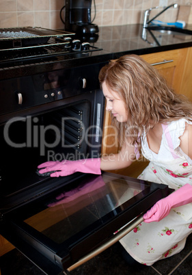 Young woman cleaning the oven