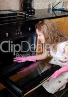 Young woman cleaning the oven