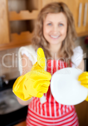 Cheerful woman with thumb up drying dish