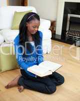 Concentrated woman reading a book sitting on the floor