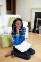 Smiling woman reading a book sitting on the floor