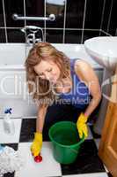 Smiling young woman cleaning bathroom's floor