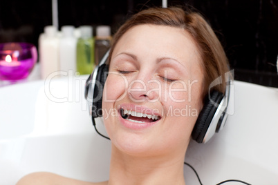 Smiling young woman listening music  in a bubble bath