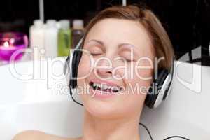Smiling young woman listening music  in a bubble bath