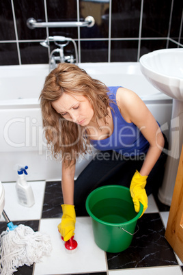 Caucasian young woman cleaning bathroom's floor