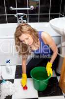 Caucasian young woman cleaning bathroom's floor