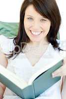 Bright woman reading a book lying on a sofa