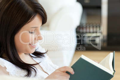 Attractive woman reading a book lying on a sofa Attractive woman reading a book lying on a sofa