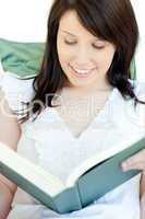 Radiant woman reading a book lying on a sofa