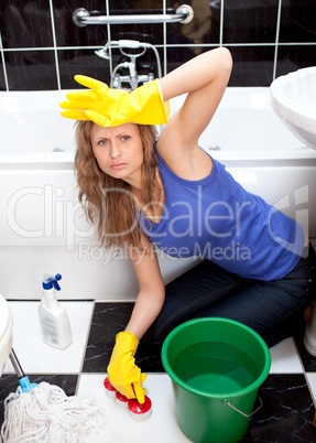 Annoyed woman cleaning bathroom's floor