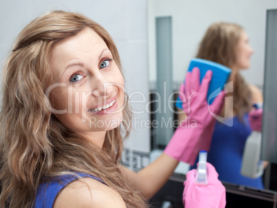 Charming woman cleaning a bathroom's mirror