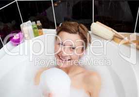 Smiling woman playing in a bubble bath