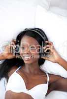 Radiant woman listening music lying on her bed