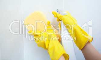 Close-up of a woman cleaning with a sponge and detergent spray