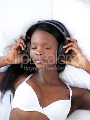Radiant woman listening music lying on her bed