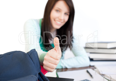 Jolly teen girl with thumb up studying