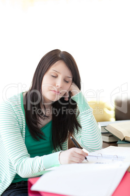 Tired young student sleeping while doing her homework