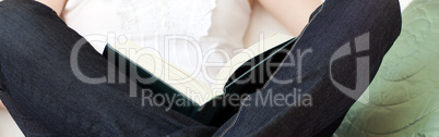 Close-up of a woman reading a book sitting on a sofa Close-up of a woman reading a book sitting on a sofa