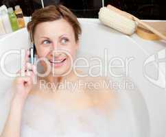 Radiant woman talking on phone in a bubble bath