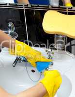 Close-up of a woman cleaning a bathroom's sink