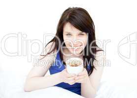 Jolly woman drinking a coffee sitting on her bed