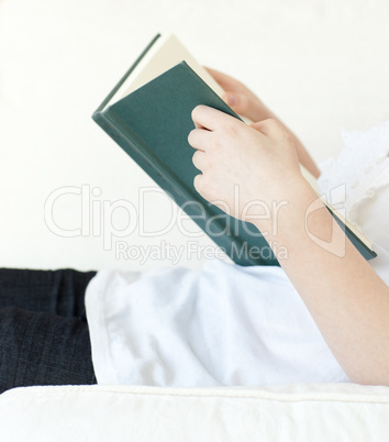 Close-up of a woman reading a book lying on a sofa