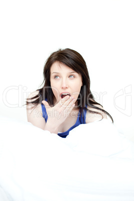 Bright woman yawning sitting on her bed