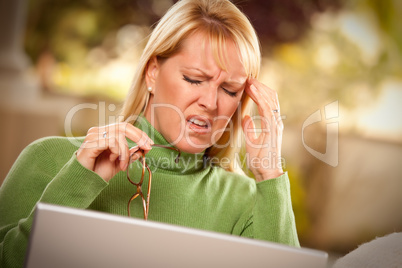 Grimacing Woman Using laptop Suffering a Headache