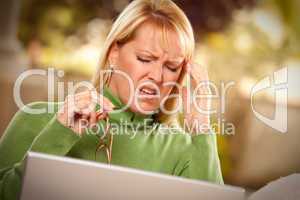 Grimacing Woman Using laptop Suffering a Headache