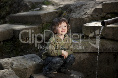Little boy sitting near spring