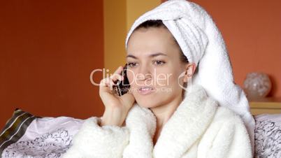 Young attractive woman in a bathrobe talking on cellular phone