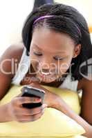 Beautiful woman sending a text lying on a sofa