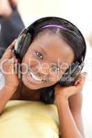 Bright woman listening music with headphones lying on a sofa