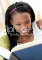Delighted teen girl studying lying on a sofa