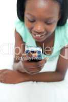 Afro-American teen girl using a mobile phone lying on her bed